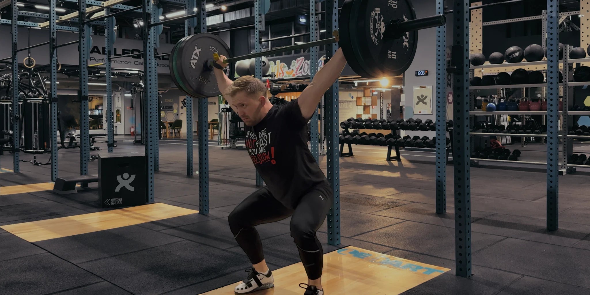 Athlete performing snatch wearing Super Weightlifting Too Slow Tee — premium black shirt made in Romania.